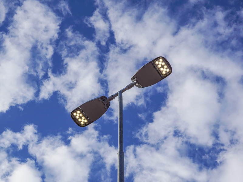 Three LED Street Lamps Affixed to an Iron Post Against a Deep Blue Sky